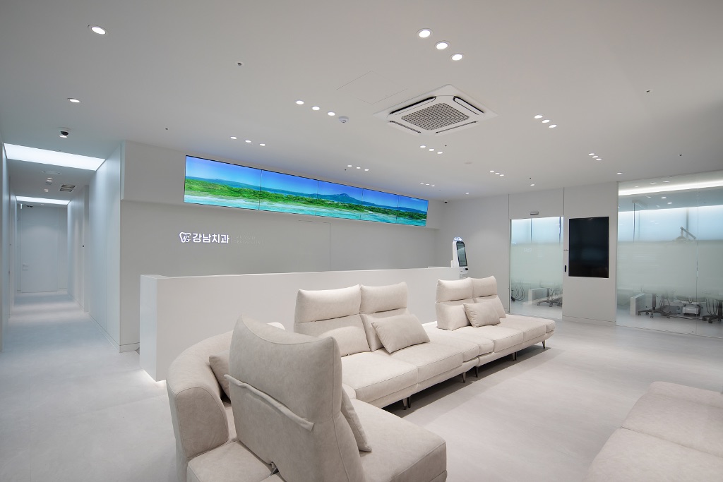 강남치과의원 대기실 전경 - 프리미엄 소파와 와이드 디스플레이